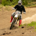 Person riding a dirt bike on a trail with trees in the background