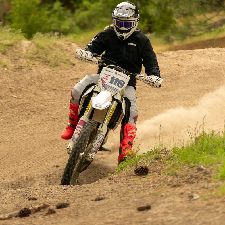 Person riding a dirt bike on a trail with trees in the background