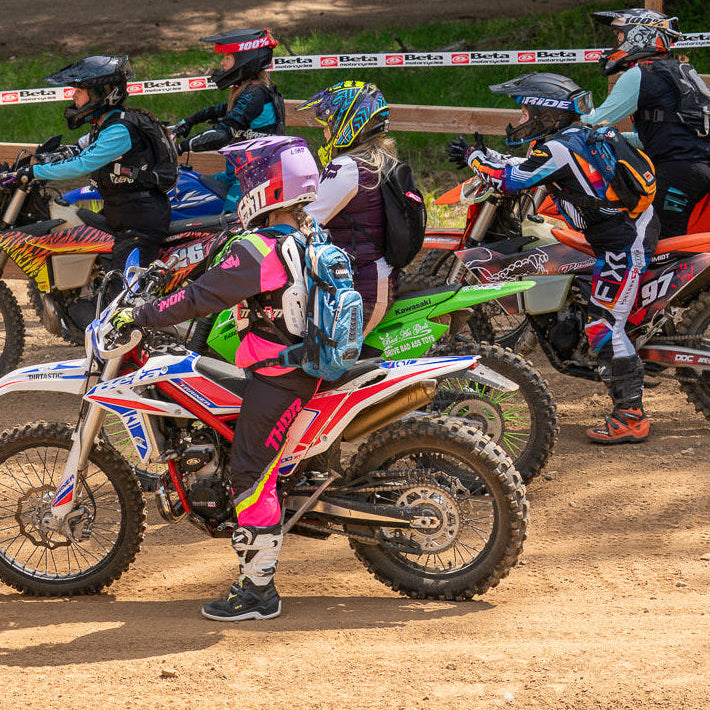 Motocross riders on their bikes at a starting line on a dirt track